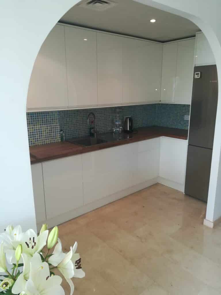 Minimalist white kitchen with turquoise tiles